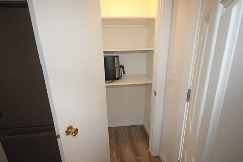 A small white closet with a shelf and a black speaker on it.