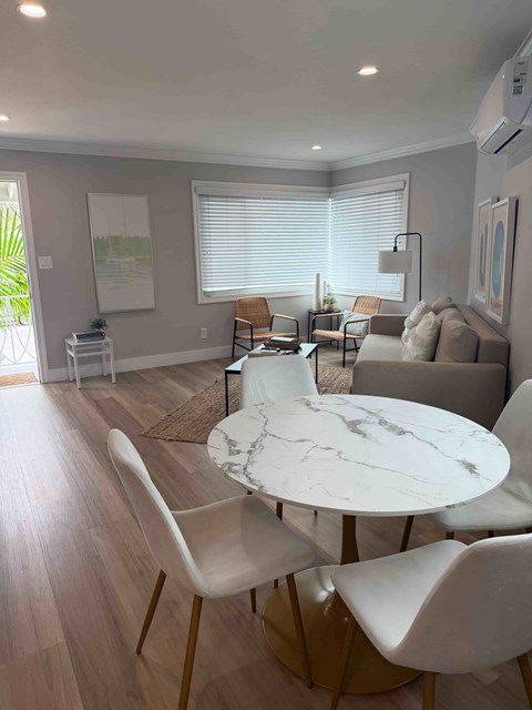 A modern living room with a white marble table and white chairs.