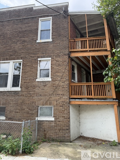 A brown brick building with a wooden balcony on the second floor.