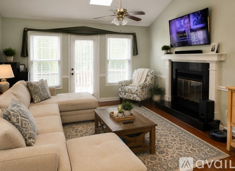 A living room with a beige couch, a coffee table, a fireplace, and a television on the wall.