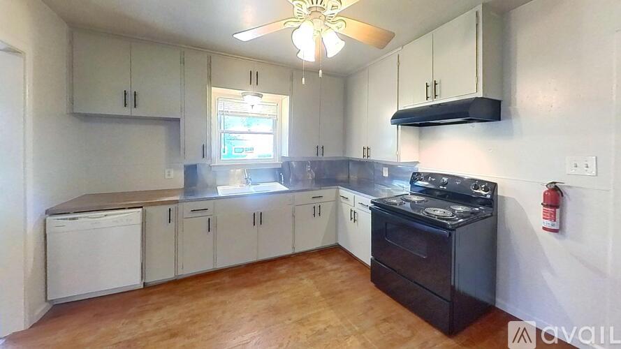 A kitchen with a black stove top oven and white cabinets.