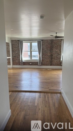 A room with wooden floors and a window with a fan.