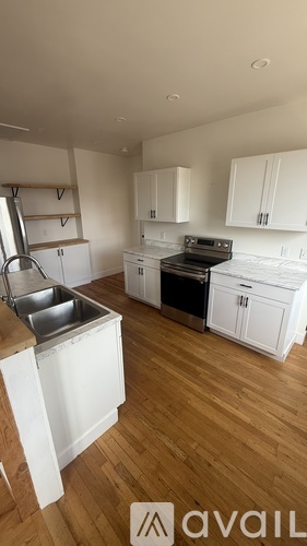 A kitchen with white cabinets and wooden floors.