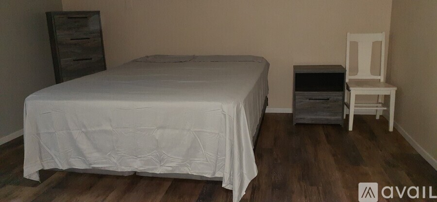 A bedroom with a bed, dresser, and chair.