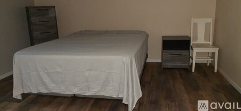 A bedroom with a bed, dresser, and chair.