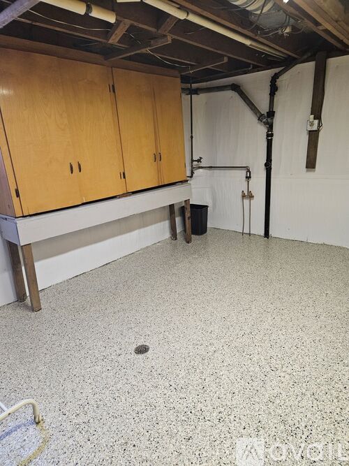 A room with wooden cabinets and a white speckled floor.