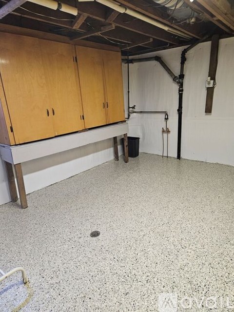 A room with wooden cabinets and a white speckled floor.