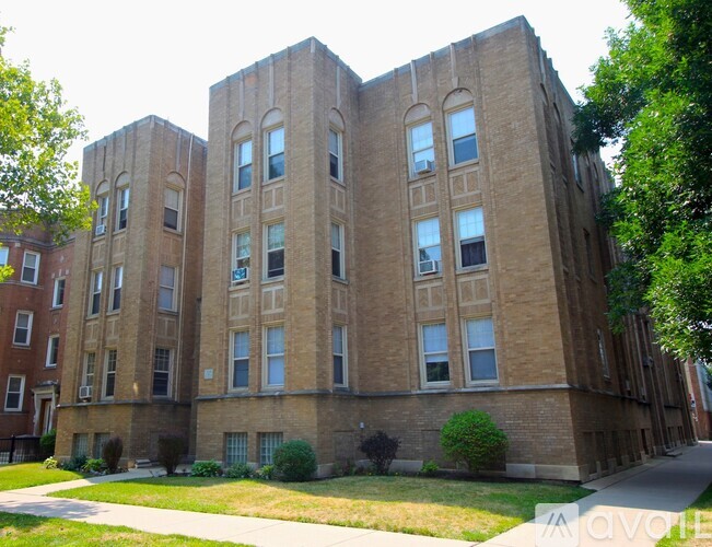 A large brick building with many windows and a green lawn in front.