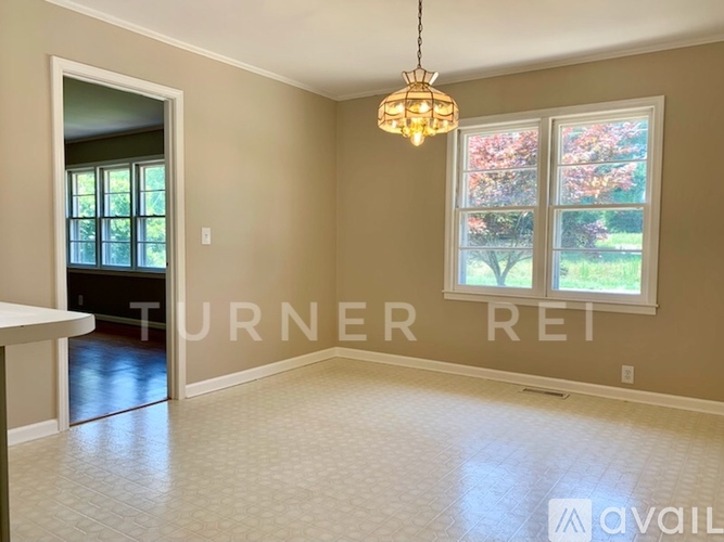 A room with a chandelier hanging from the ceiling and a window with a view of trees.