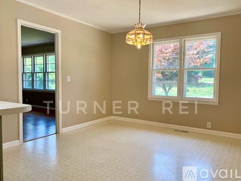 A room with a chandelier hanging from the ceiling and a window with a view of trees.