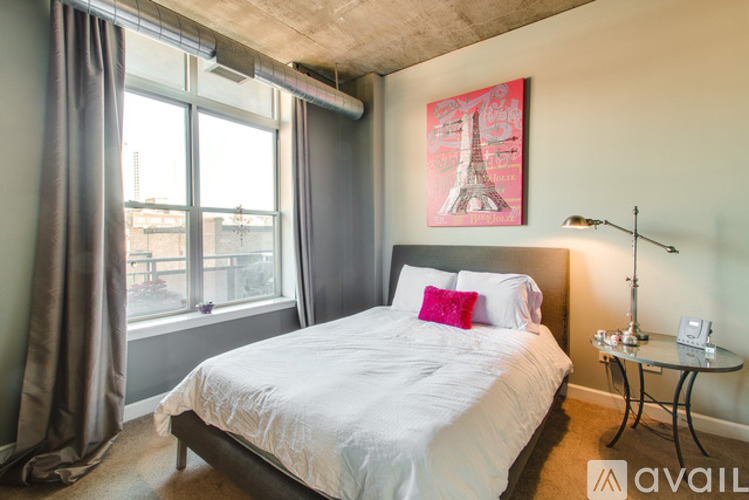 A bedroom with a large bed and a picture of the Eiffel Tower on the wall.