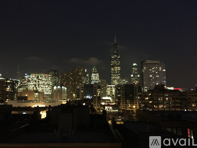 A city skyline at night with the tallest building lit up in green.