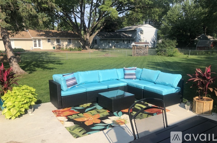 A blue couch is on a patio with a table and chairs.
