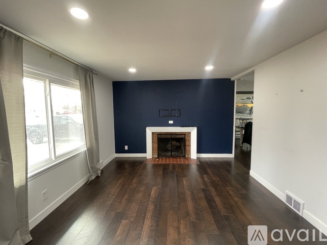A spacious room with a fireplace and wooden flooring.