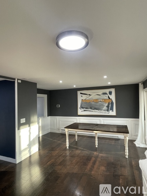 A modern living room with a bench and a painting on the wall.