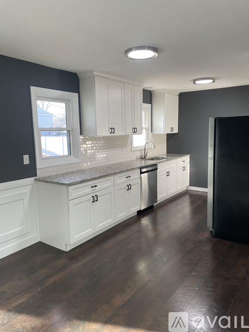 A kitchen with white cabinets and a black refrigerator.