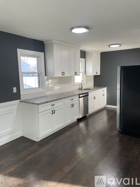 A kitchen with white cabinets and a black refrigerator.