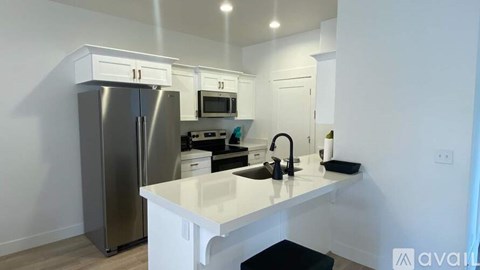 A kitchen with white cabinets and a stainless steel refrigerator.