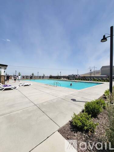 A swimming pool surrounded by a concrete patio and some greenery.