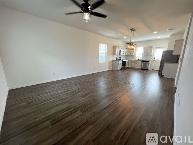 A spacious room with wooden flooring and a ceiling fan.
