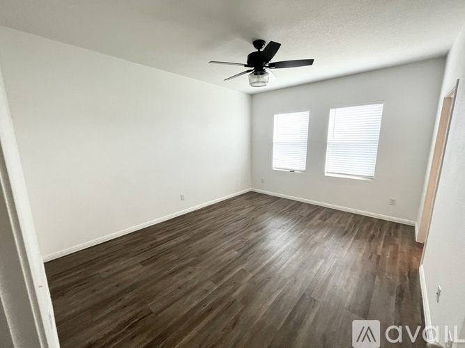 A room with a ceiling fan and wood flooring.