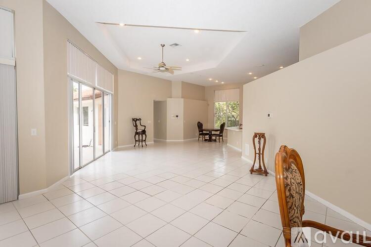 A spacious living room with a white tiled floor and a ceiling fan.