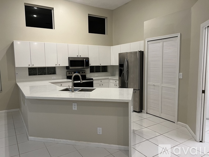 A kitchen with white cabinets and a black fridge.
