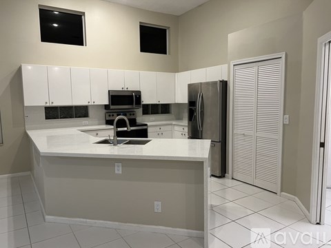 A kitchen with white cabinets and a black fridge.