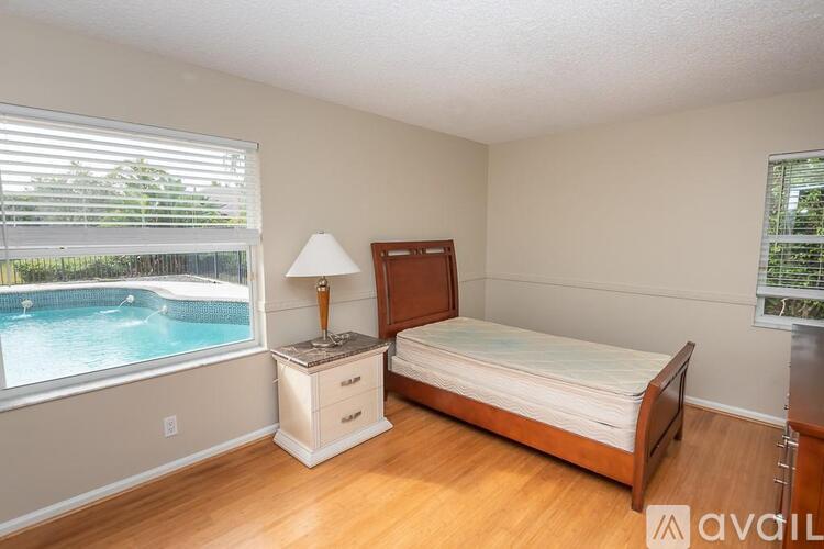 A bedroom with a bed, nightstand, and window overlooking a pool.