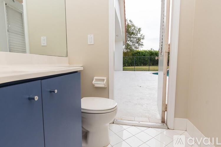 A bathroom with a toilet, sink, and a door leading to a pool.