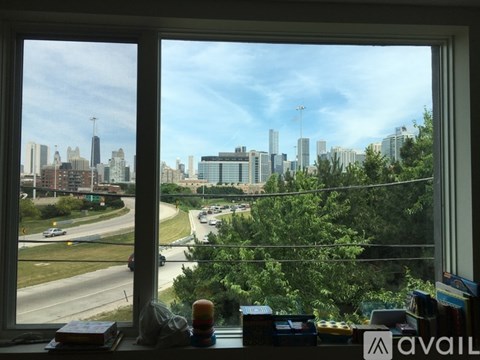 A view of a city skyline from a window with a book and a candle on the windowsill.