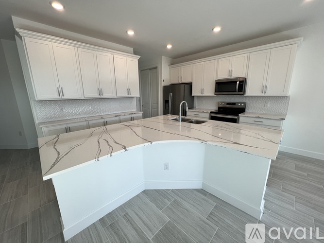 A kitchen with a marble countertop and white cabinets.