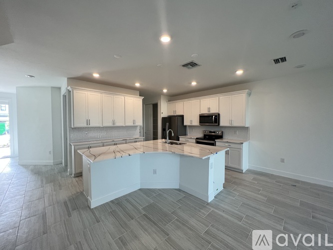A modern kitchen with a large island and wooden flooring.