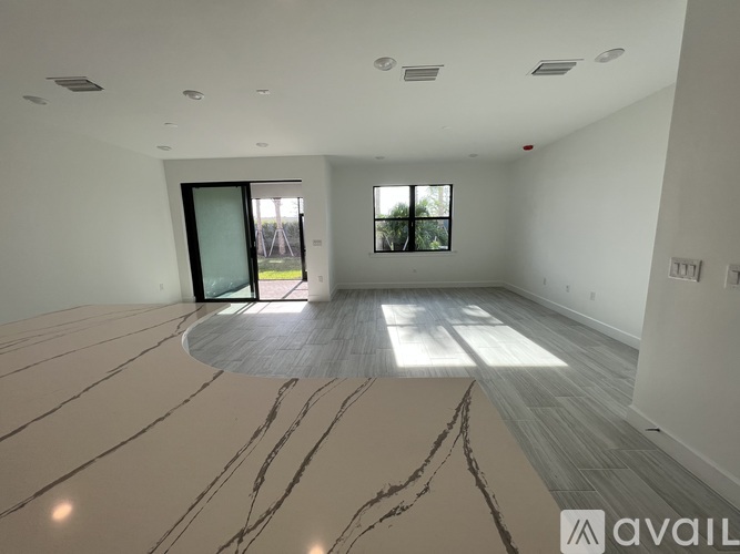 A spacious room with marble flooring and a large window.