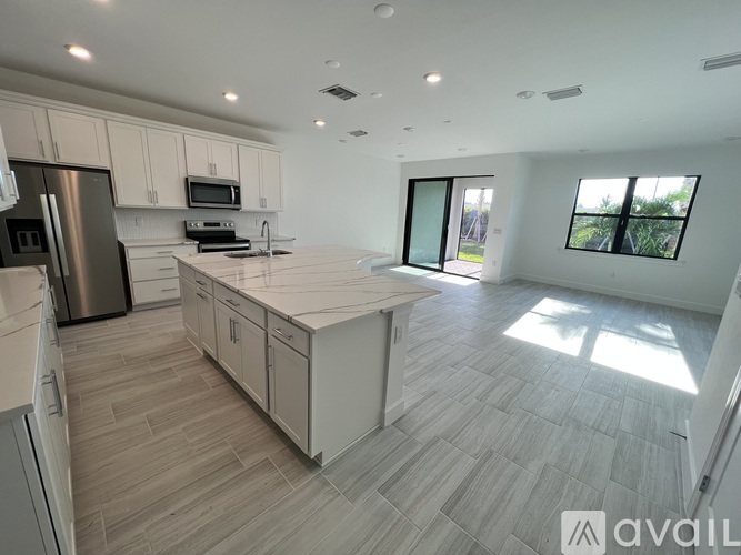 A modern kitchen with a refrigerator, microwave, oven, and sink.