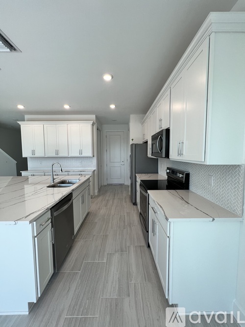 A modern kitchen with white cabinets and a wooden floor.