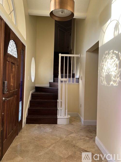 A hallway with a wooden door and a staircase with white railings.