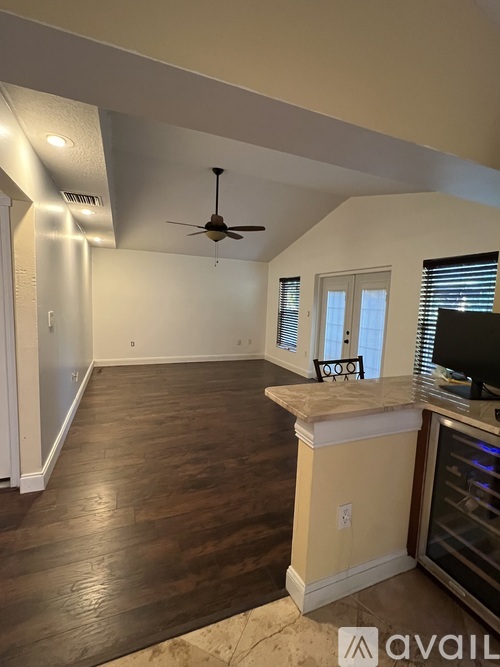 A spacious room with a ceiling fan and wooden flooring.