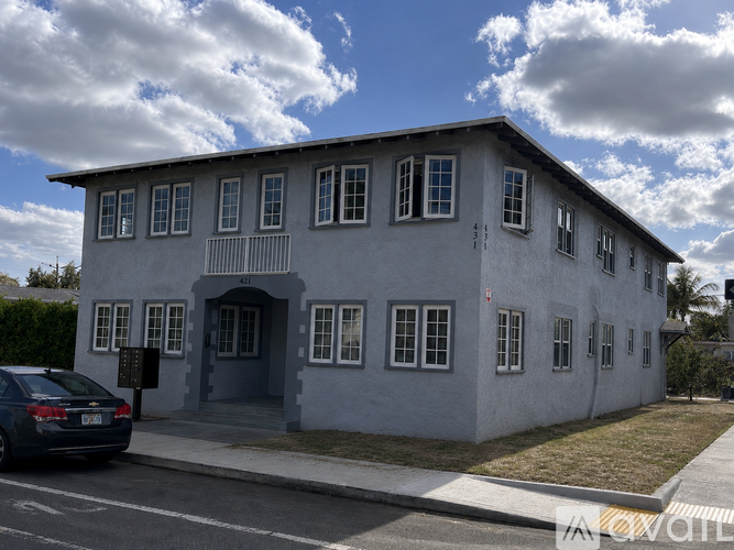 A grey building with a car parked in front.