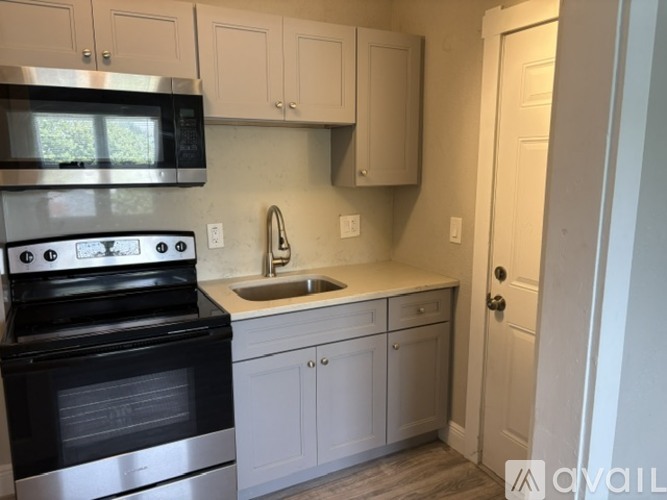 A kitchen with a black stove top oven and white cabinets.
