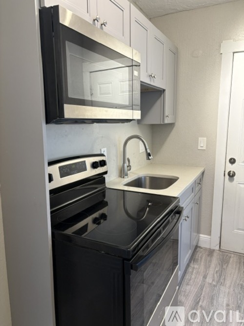A kitchen with black appliances and white cabinets.
