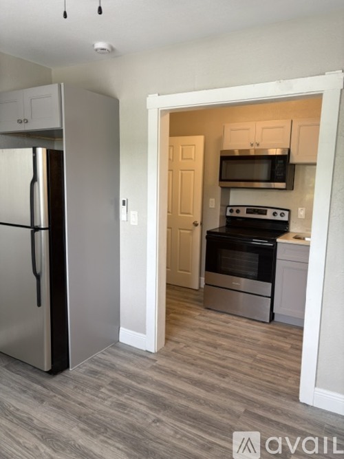 A kitchen with a refrigerator, microwave, oven, and cabinets.