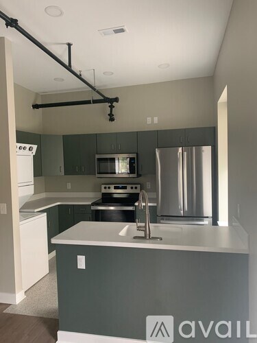 A kitchen with a white counter top and a stainless steel refrigerator.