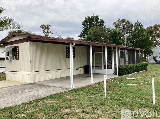 A small building with a brown roof and a white fence in front.