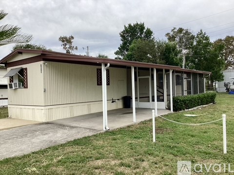 A small building with a brown roof and a white fence in front.