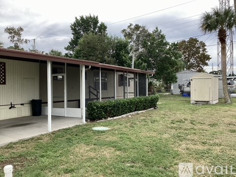 A building with a brown roof and a white door is surrounded by a grassy area.