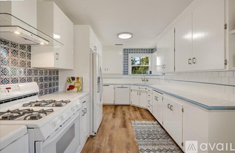 A kitchen with white cabinets and a patterned backsplash.