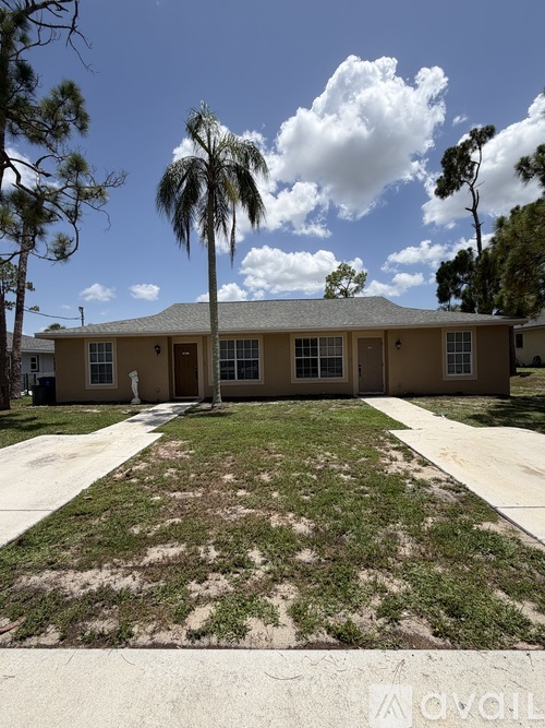 A house with a brown roof and a white door is surrounded by trees and grass.