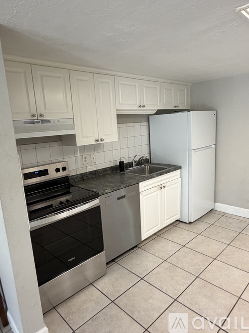 A kitchen with white cabinets and a stainless steel refrigerator.
