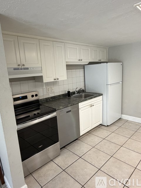 A kitchen with white cabinets and a stainless steel refrigerator.